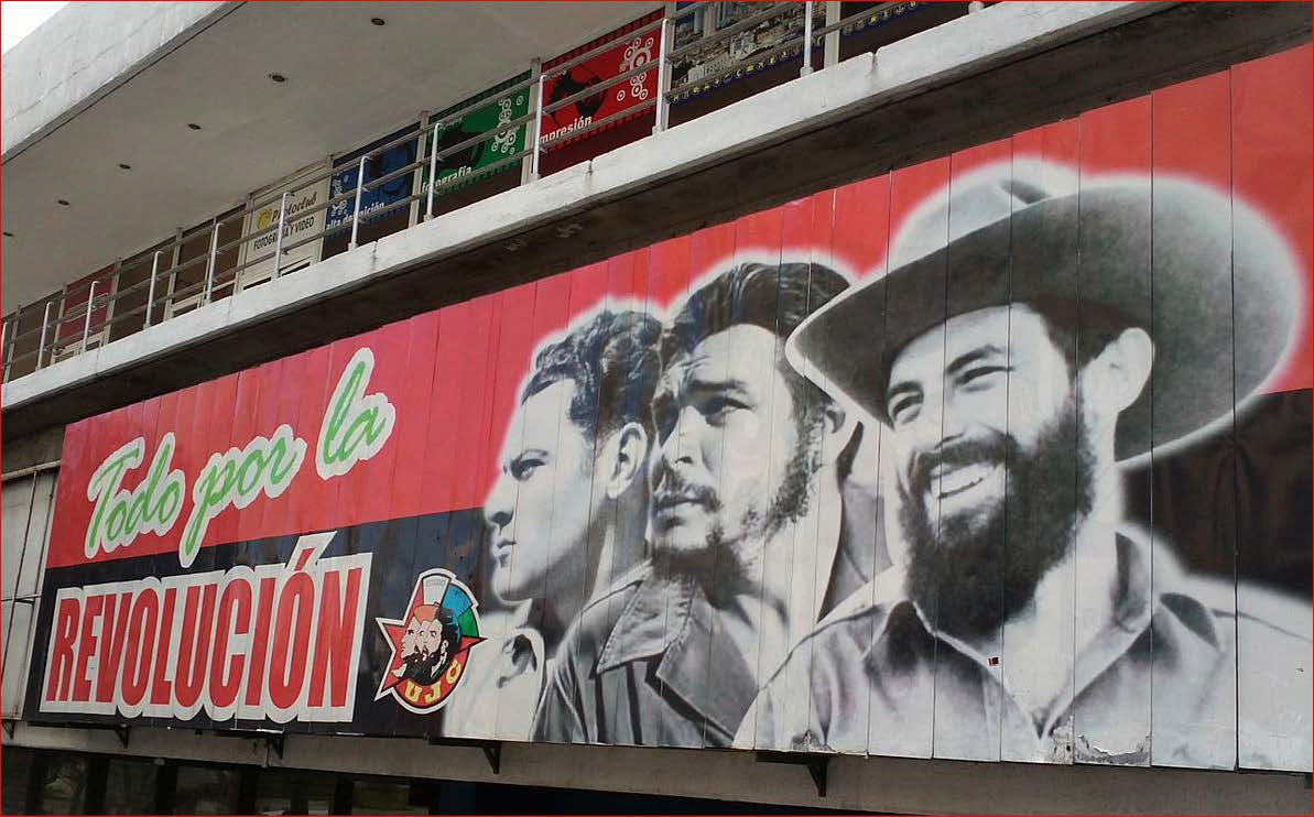A poster on the side of a building with the faces of three key people from the Cuban Revolution.