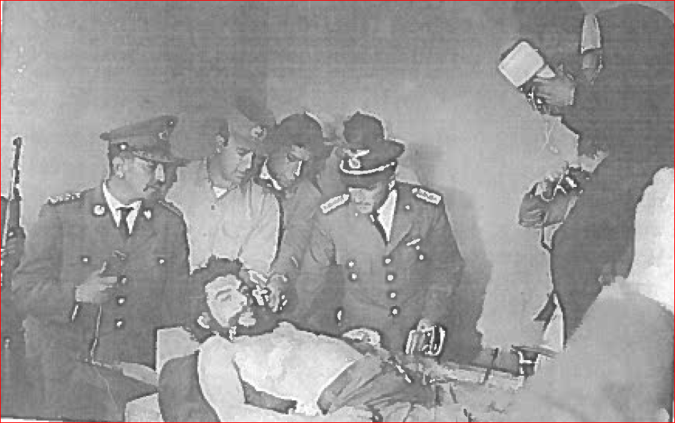 A black and white photograph of Che Guevara surrounded by several men who are dressed in military uniforms.